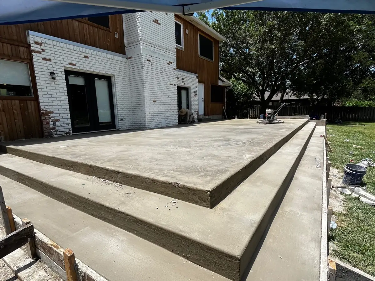 Finished backyard concrete patio with a poured step-down at a Hill Country home