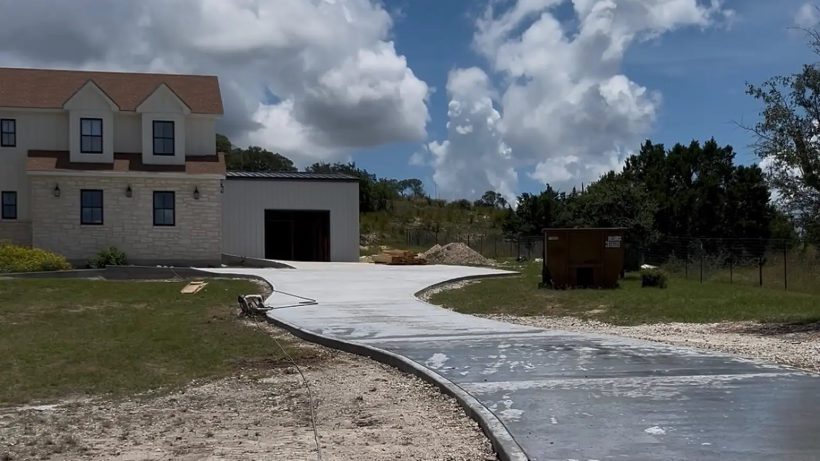 New concrete driveway leading to a Texas Hill Country home