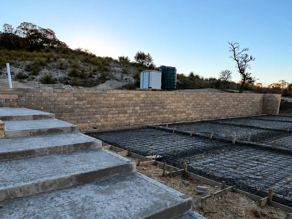 Block retaining wall with poured concrete steps holding a hillside bank