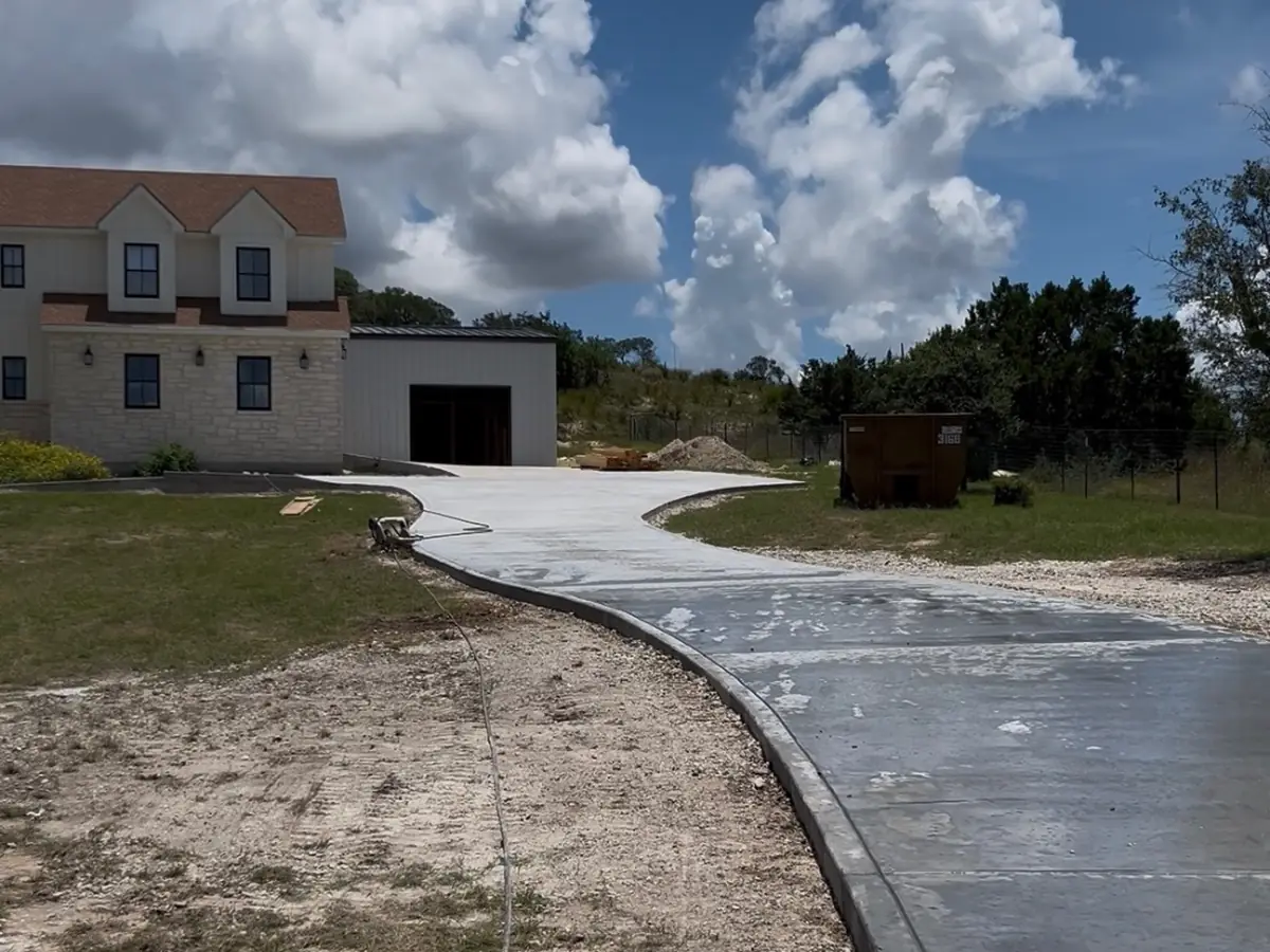 Finished curved concrete driveway leading to a Texas Hill Country home